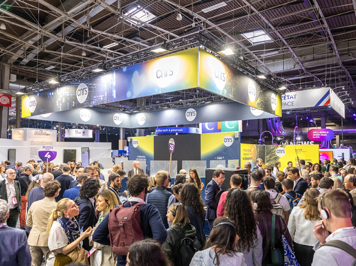 stand CNRS VivaTech 2024 ; intérieur jour, foule de personnes au premier plan, plafond avec fenêtres carrées et armature métalliques
